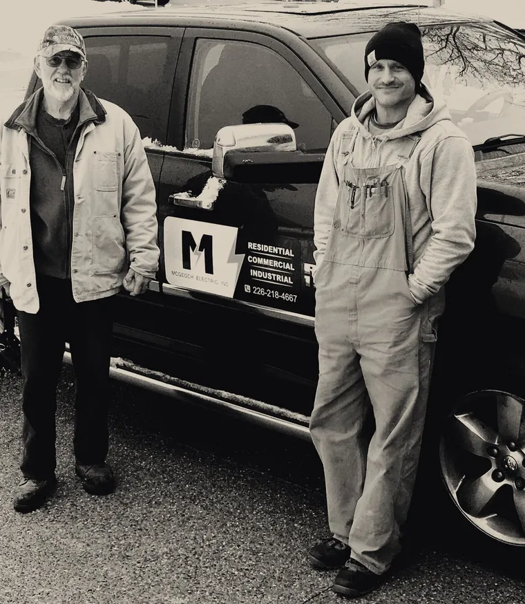 Two generations of the McGeoch family beside the lettered company truck